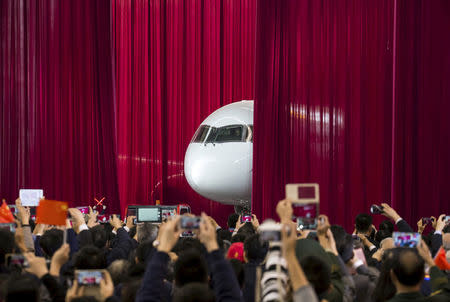 FILE PHOTO: People take pictures and videos as the first C919 passenger jet made by the Commercial Aircraft Corp of China (Comac) is pulled out from behind a curtain during a news conference at the company's factory in Shanghai, November 2, 2015. REUTERS/China Daily/File Photo