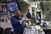 Barber Sami Matta, left, gives a haircut to Steve Perosino, of Dedham, Mass., right, at Chris & Sam's Barbershop, in Norwood, Mass., Monday, March 23, 2020. The Barbershop is to close by noon Tuesday, March 24, in keeping with Mass. Gov. Charlie Baker's order that all non-essential businesses close at noon Tuesday and remain closed through Tuesday, April 7, out of concern about the spread of the coronavirus. For most people, the new coronavirus causes only mild or moderate symptoms, such as fever and cough. For some, especially older adults and people with existing health problems, it can cause more severe illness, including pneumonia. The vast majority of people recover from the new virus. (AP Photo/Steven Senne)