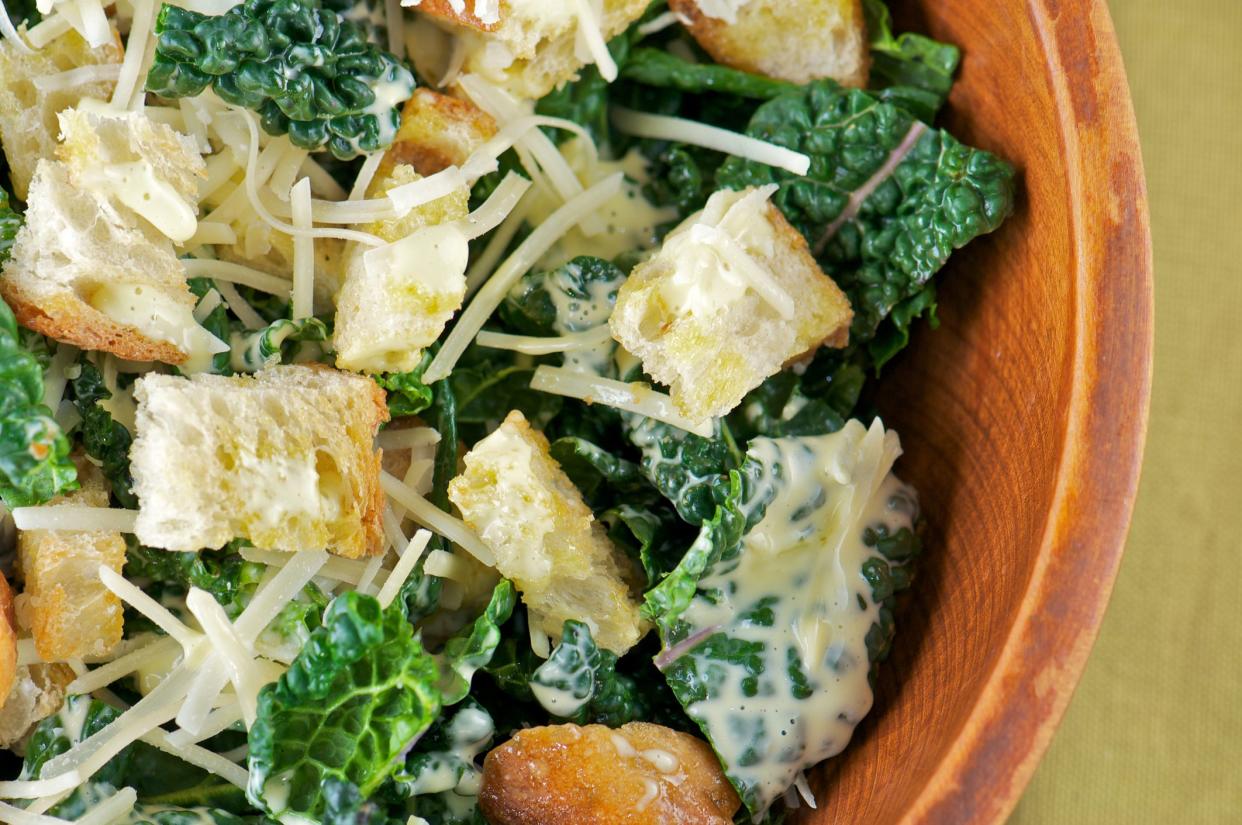 Close-up of kale caesar salad  in wooden salad bowl from above