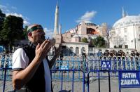 A Muslim man prays in front of the Hagia Sophia or Ayasofya, after a court decision that paves the way for it to be converted from a museum back into a mosque, in Istanbul