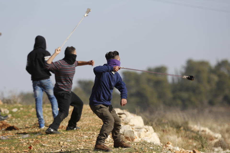 FILE - Palestinian demonstrators throw stones during clashes with Israeli troops following a demonstration in support of Palestinian prisoners in Nabi Saleh, Jan. 13, 2018, near the West Bank city of Ramallah. In negotiations with Israel to free hostages in Hamas captivity in Gaza, the militant group has pushed for the release of high-profile prisoners. But most Palestinians passing through Israel’s ever-revolving prison door are young men arrested in the middle of the night for throwing stones and firebombs in villages near Israeli settlements. Nabi Saleh is one such village, long known for its grassroots protest movement. (AP Photo/Majdi Mohammed, File)