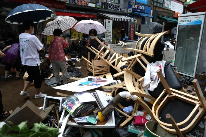 People clean up debris at a traditional market damaged by flood after torrential rain in Seoul on Tuesday.