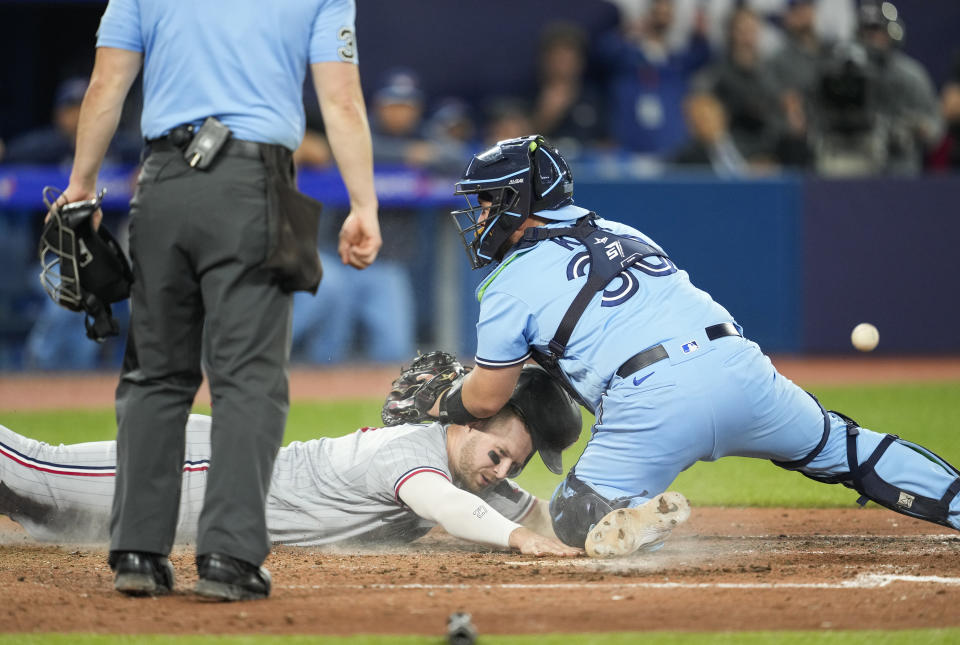 Minnesota Twins' Ryan Jeffers (27) scores on a sacrifice fly by Michael A. Taylor, while Toronto Blue Jays catcher Alejandro Kirk makes a tag without the ball during the 10th inning of a baseball game Friday, June 9, 2023, in Toronto. (Mark Blinch/The Canadian Press via AP