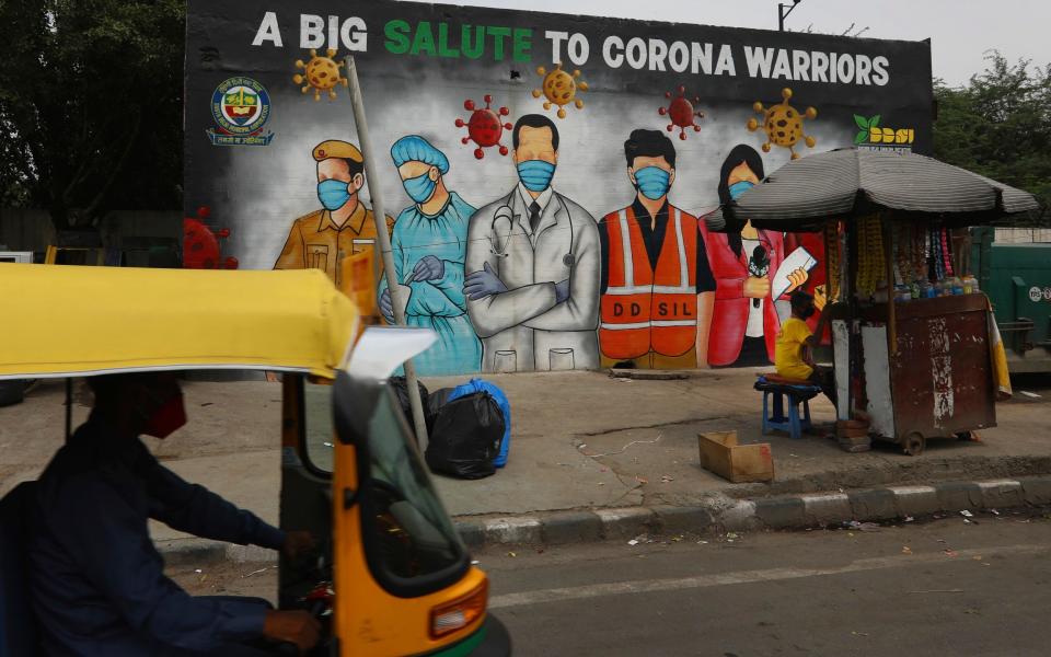 An autorickshaw drives past a graffiti thanking frontline workers in the fight against the coronavirus, in New Delhi, India - Manish Swarup /AP