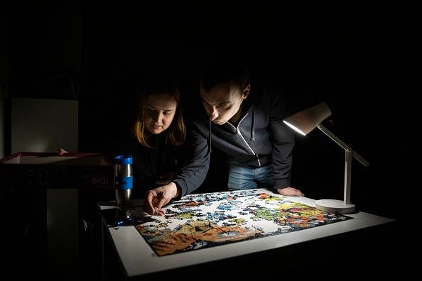 Alina and Igor try to complete a jigsaw puzzle in their apartment block in near-total darkness during a scheduled power cut on Nov. 6, 2022, in Kyiv.