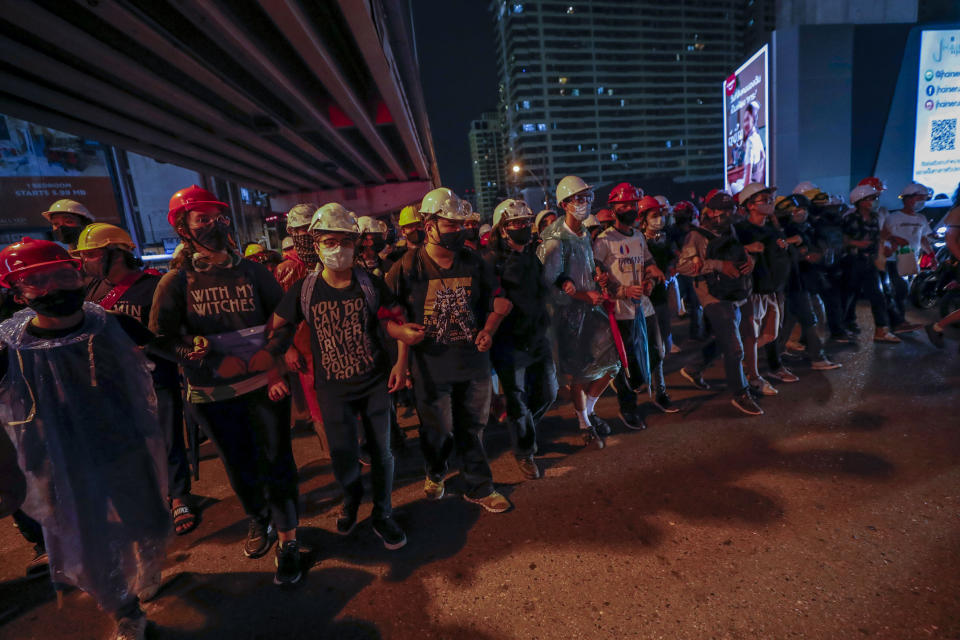 Pro-democracy activists create a human chain to confront a police barricades during their march to the Government House, prime minister's office during a protest march in Bangkok, Thailand, Wednesday, Oct. 21, 2020. Thailand's prime minister on Wednesday pleaded with his countrymen to resolve their political differences through Parliament, as student-led protests seeking to bring his government down continued for an eighth straight day. (AP Photo/Sakchai Lalit)