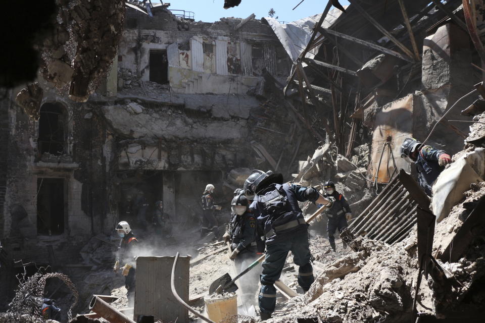 FILE - Donetsk People Republic Emergency Situations Ministry employees clear rubble at the side of the damaged Mariupol theater building during heavy fighting in Mariupol, eastern Ukraine, on May 12, 2022. By ending 77 years of almost uninterrupted peace in Europe, war in Ukraine war has joined the dawn of the nuclear age and the birth of manned spaceflight as a watershed in history. After nearly a half-year of fighting, tens of thousands of dead and wounded on both sides, massive disruptions to supplies of energy, food and financial stability, the world is no longer as it was. (AP Photo)