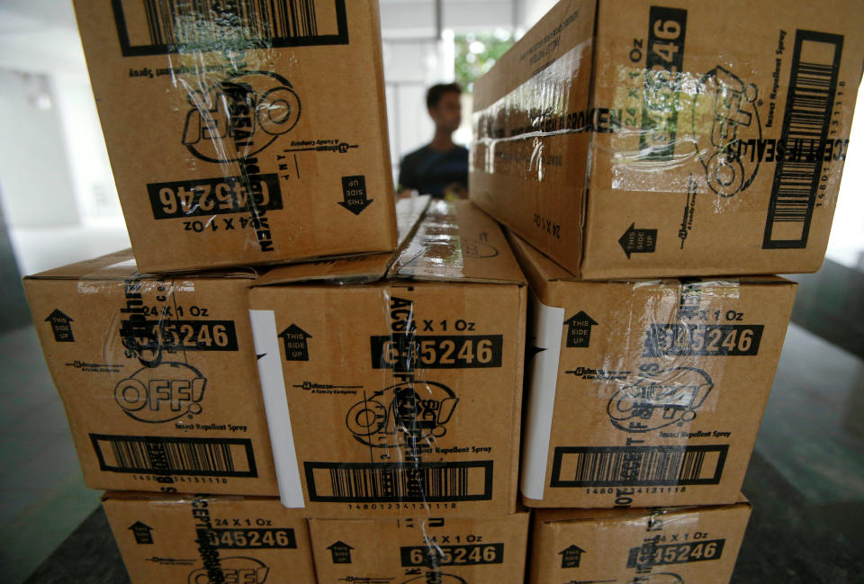 A volunteer sits behind boxes of insect repellents to be distributed to residents at a new Zika cluster area in Singapore