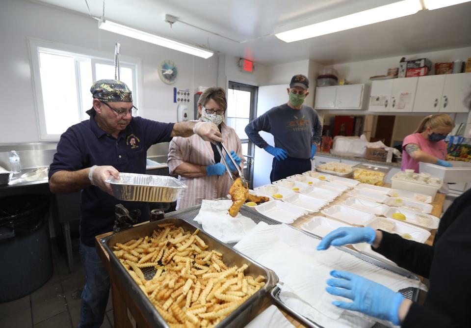 The Ely-Fagan Post 1151 American Legion fish fry continued as a drive-through during the early days of the COVID-19 pandemic. In this March 27, 2020, photo, Ray Torres puts a cooked fish in a to go container for Sandy Junge.