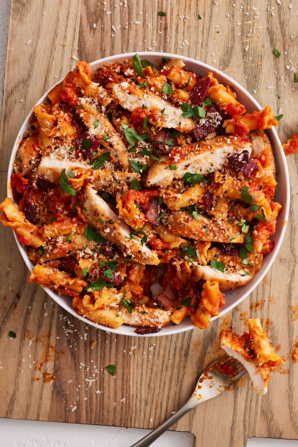 chicken parm pasta in a white bowl on a wooden background