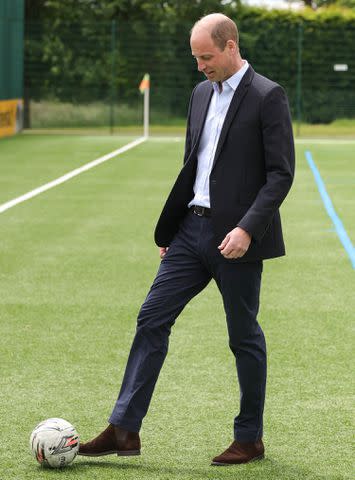 <p>Andrew Parsons / Kensington Palace</p> Prince William kicks a soccer ball at St. George's Park on June 10, 2024.