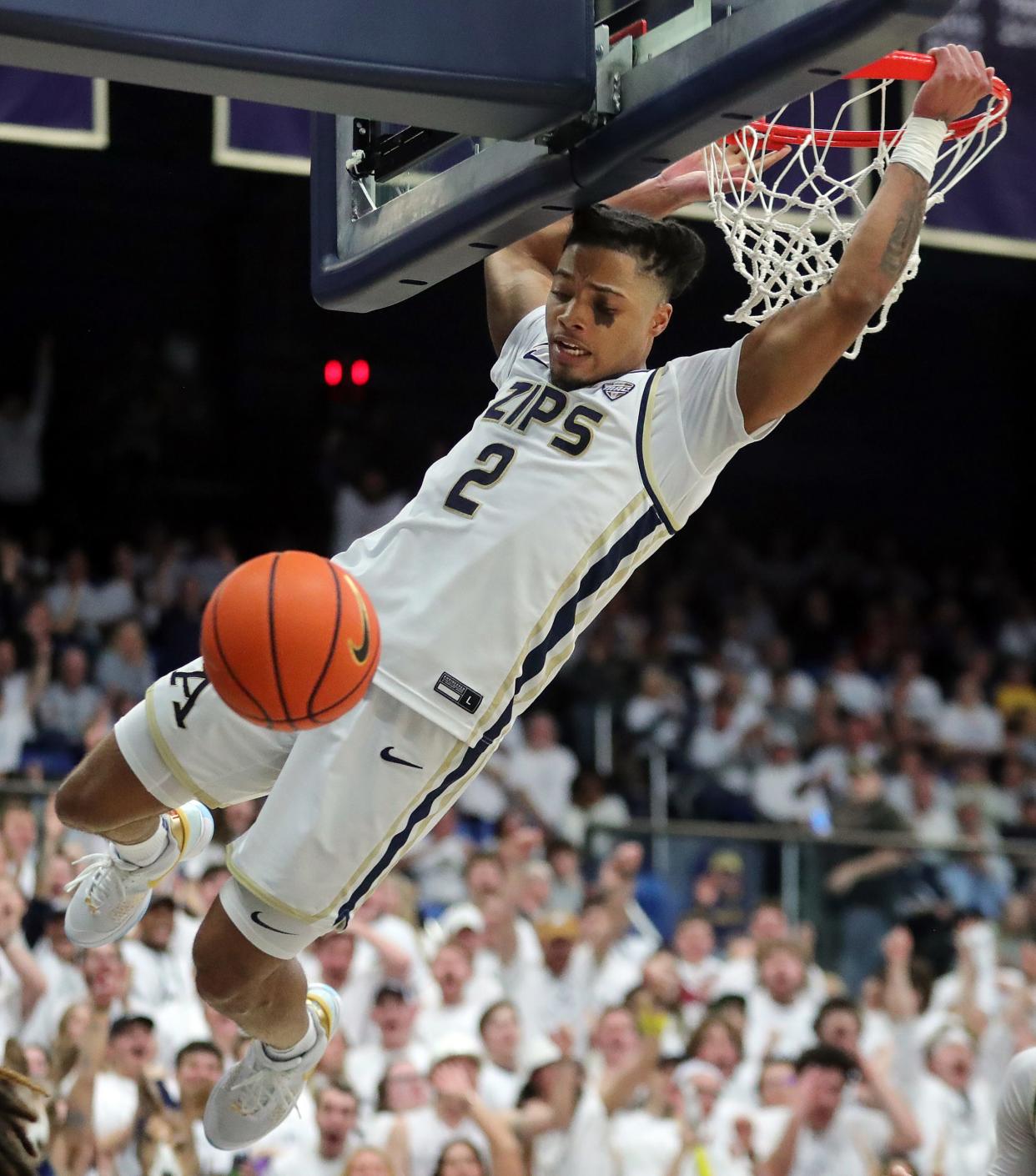 Akron Zips guard Greg Tribble (2) hangs on the rim after a first-half dunk against Kent State, Friday, Feb. 23, 2024.