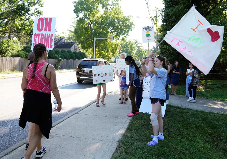 Melina Spiropoulos, right, waves a "I Love My Teachers" flag as teachers, parents and students walk the picket line as Columbus Education Association strike at Whetstone High School in Columbus, Ohio on Aug. 24, 2022.