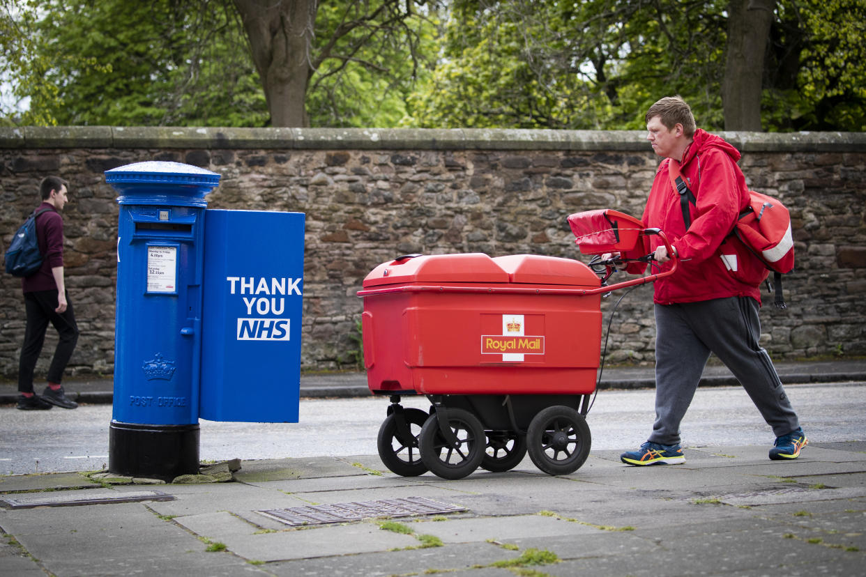Postman Graeme Byers passes by one of the specially decorated postboxes in Edinburgh painted blue in support of NHS workers and carers fighting the coronavirus pandemic. (Photo by Jane Barlow/PA Images via Getty Images)