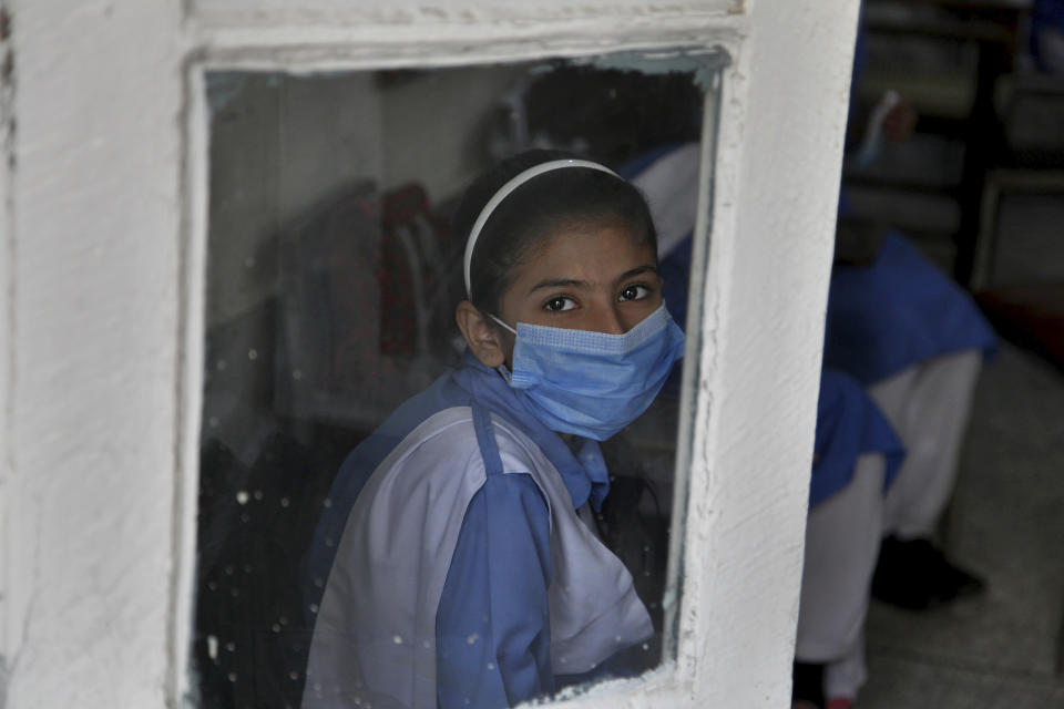A student wearing a face mask to prevent the spread of the coronavirus looks out from her classroom at a primary school in Peshawar, Pakistan, Wednesday, Sept. 30, 2020. Pakistani students head back to primary schools following their reopening, amid a steady decline in coronavirus deaths and infections. (AP Photo/Muhammad Sajjad)