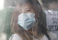 A woman wearing a protective mask looks out from a bus during the first day of a more relaxed lockdown that was placed to prevent the spread of the new coronavirus in Manila, Philippines on Monday, June 1, 2020. Traffic jams and crowds of commuters are back in the Philippine capital, which shifted to a more relaxed quarantine with limited public transport in a high-stakes gamble to slowly reopen the economy while fighting the coronavirus outbreak. (AP Photo/Aaron Favila)