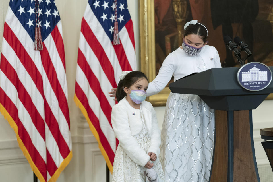 Little caregivers Gabby Rodrigues pats her little sister Eva Rodriguez' back as she speaks in the East Room during a ceremony at the White House honoring children in military and veteran caregiving families, Wednesday, Nov. 10, 2021. (AP Photo/Manuel Balce Ceneta)