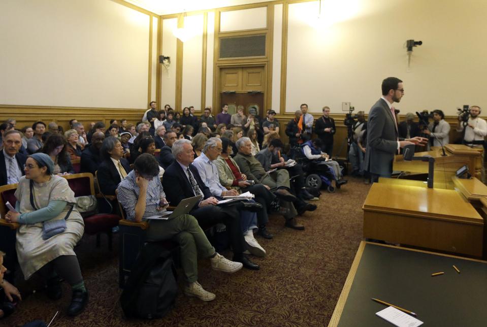 San Francisco Supervisor Scott Wiener, right, speaks in favor of employee shuttles Tuesday, Jan. 21, 2014, before the San Francisco Municipal Transportation Authority board of directors at a SFMTA meeting at City Hall in San Francisco. San Francisco officials voted in favor of a proposal to start regulating employee shuttles for companies like Google, Facebook and Apple, charging a fee for those that use public bus stops and controlling where they load and unload. Private shuttle buses have created traffic problems, blocking public bus stops during peak commute hours. (AP Photo/Jeff Chiu)