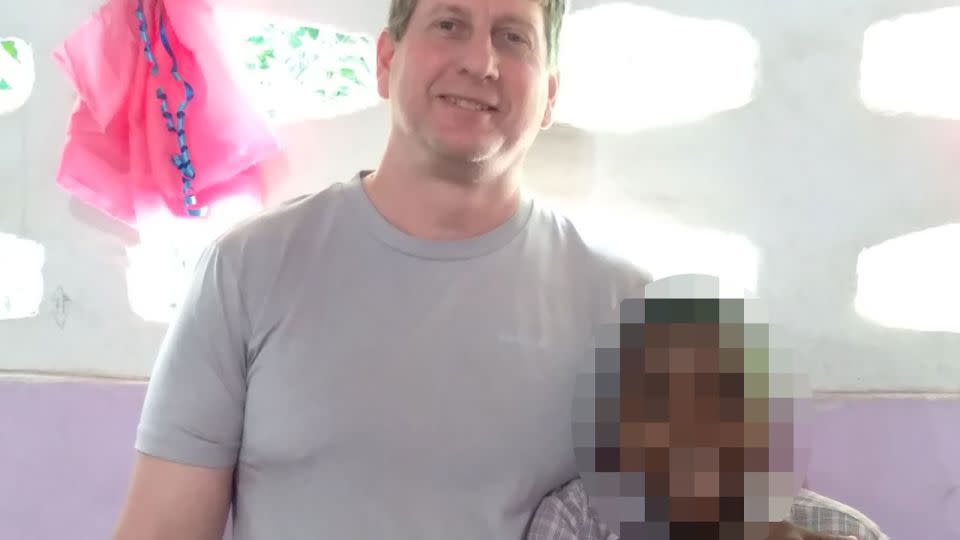 John Tennant is seen in an undated photo with one of the two teens the couple adopted from Haiti. CNN blurred the child's face to protect his identity. - Courtesy Missy Tennant