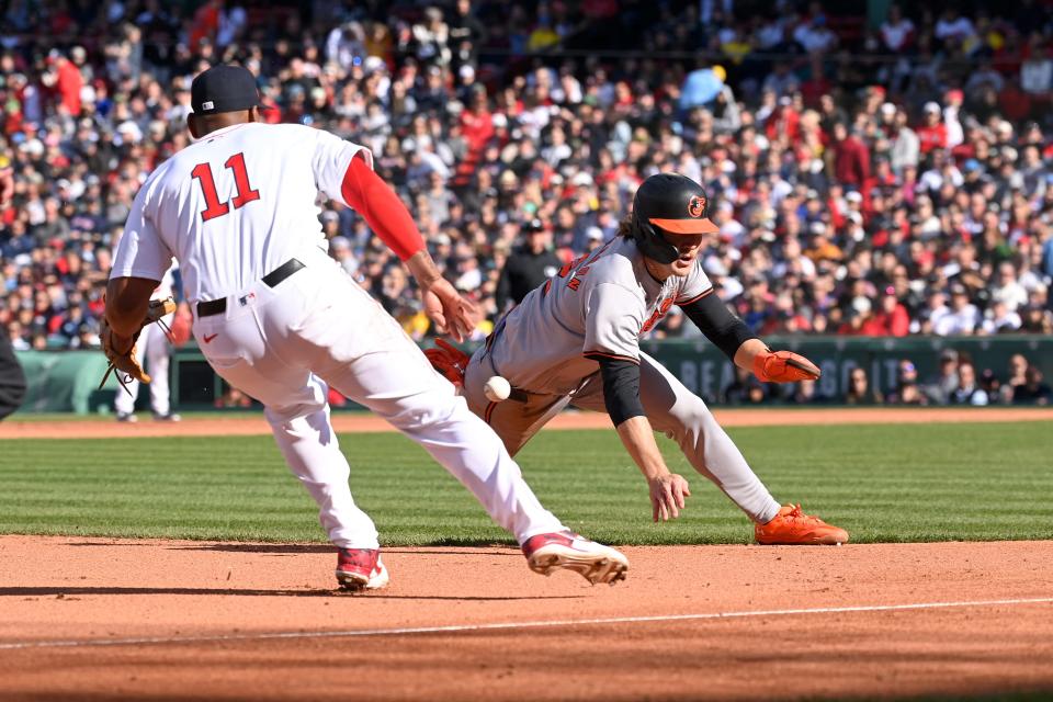 The Orioles' Gunnar Henderson steals third base as the Red Sox's Rafael Devers moves to cover during the seventh inning of Tuesday's game at Fenway Park.