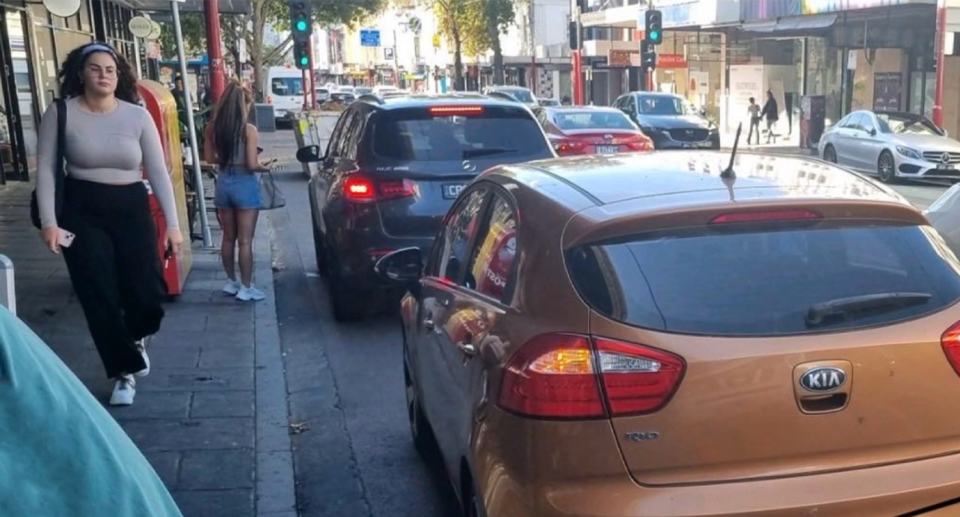 The photographic evidence included with the parking infringement shows the orange car parked on the street as the woman approaches it.