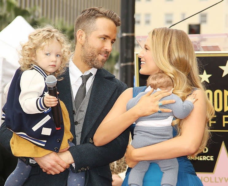 Blake Lively and Ryan Reynolds each holding one of their children