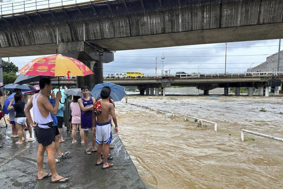 CORRECTS PHOTOGRAPHER'S LAST NAME TO CALUPITAN - Residents watch the Marikina river as it floods from monsoon rains worsened by offshore typhoon Gaemi on Wednesday, July 24, 2024, near Manila, Philippines. (AP Photo/Joeal Calupitan)