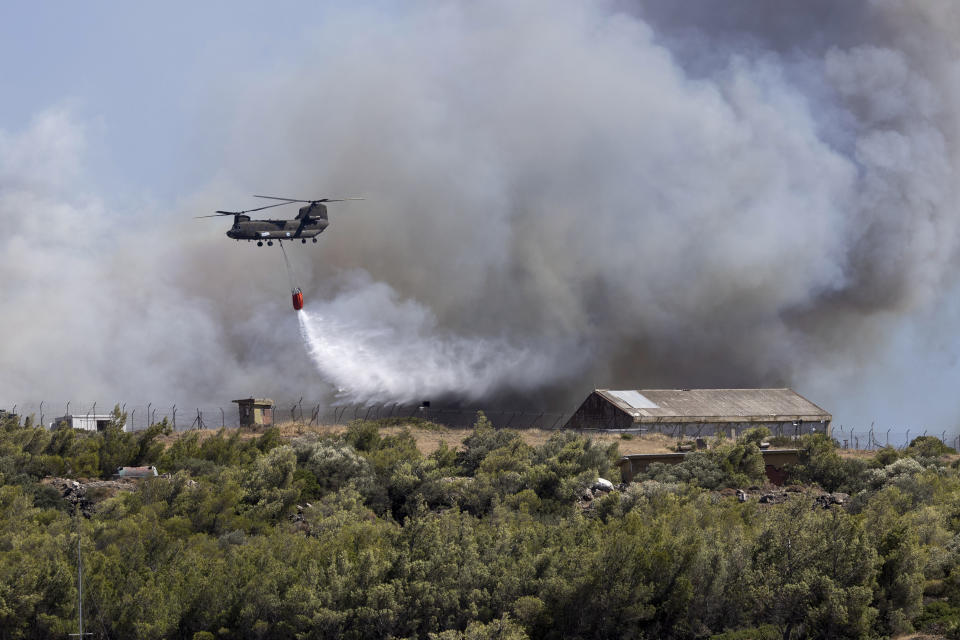 A Chinook helicopter drops water over a wildfire at Keratea area, southeast of Athens, Greece, Sunday, June 30, 2024. (AP Photo/Yorgos Karahalis)