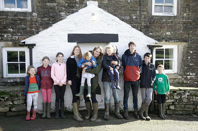 Amanda Owen and her children stand in front of house