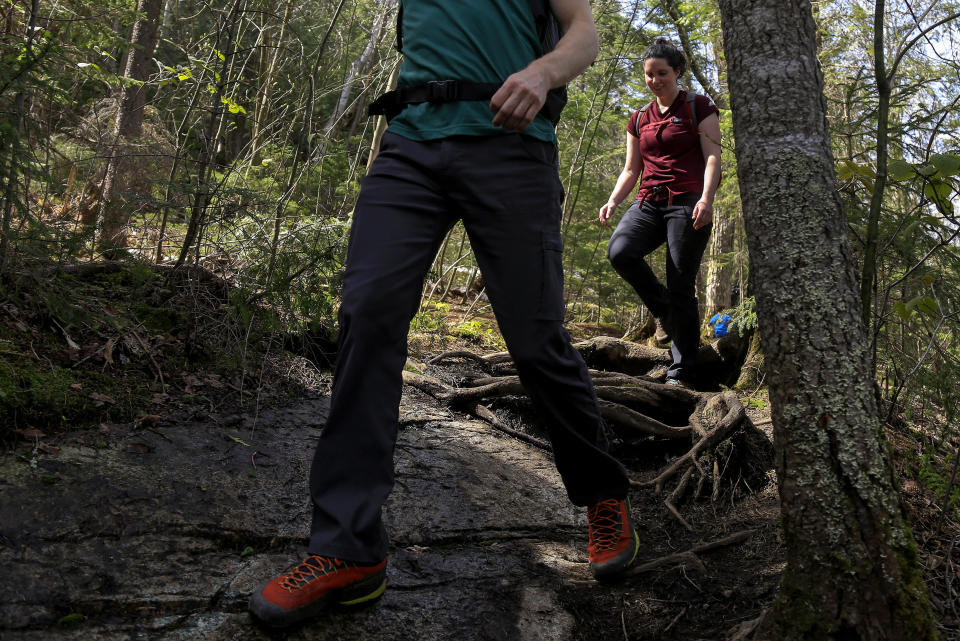 Kelsey Crosby, right, and Matt Hockemeyer descend the trail from Indian Head summit, Saturday, May 15, 2021, near St Huberts, N.Y. A free reservation system went online recently to control the growing number of visitors packing the parking lot and tramping on the trails through the private land of the Adirondack Mountain Reserve. The increasingly common requirements, in effect from Maui to Maine, offer a trade-off to visitors, sacrificing spontaneity and ease of access for benefits like guaranteed parking spots and more elbow room in the woods. (AP Photo/Julie Jacobson)