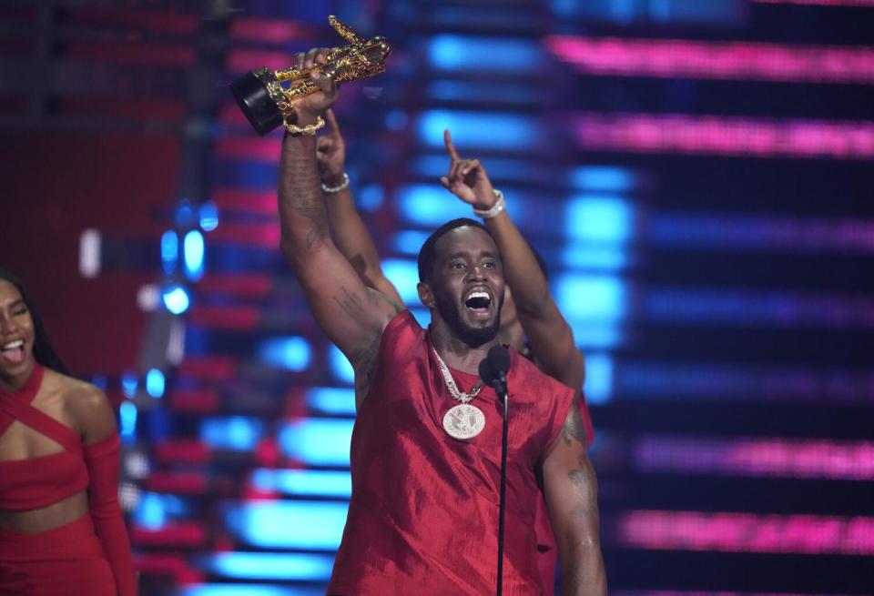 Sean "Diddy" Combs holds an award up and cheers.