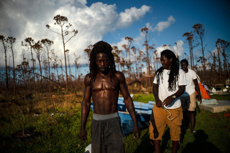 Dexter Edwards, front, his brother Nathanael Edwards right, and his cousin Valentino Ingraham walk amid one of their family's homes destroyed by Hurricane Dorian in Rocky Creek East End, Grand Bahama, Bahamas, Sept. 8, 2019. 