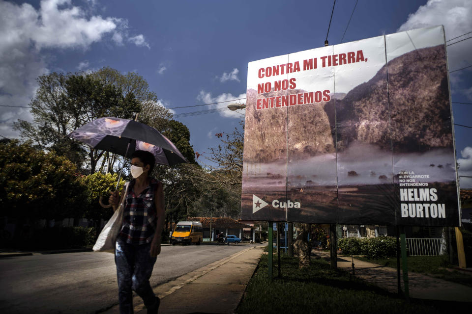 A woman walks past an anti-embargo sign that reads in Spanish: "Against my land, we don't understand each other" in Viñales, Cuba, March 1, 2021. Both U.S. sanctions meant to punish the government and a COVID-19 pandemic have squashed tourism almost everywhere, making some Cubans hope that new U.S. President Joe Biden will reverse at least some of the restrictions implemented by his predecessor. (AP Photo/Ramon Espinosa)