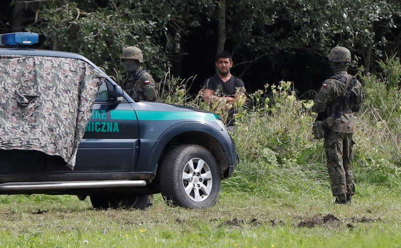 FILE PHOTO: Polish border patrol officers pictured next to a migrant stranded on the border between Belarus and Poland