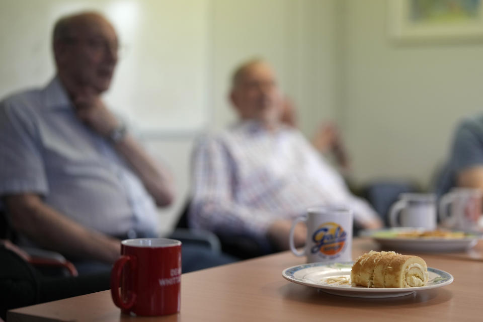 Cups of tea and coffee with creme cake on the plastic table during a weekly lunch meeting of some 20 retired men at the Tredegar community centre in Bow, in east London, Thursday, May 16, 2024. Passing around plates of cheese and crackers and slices of crème cake, they drank steaming coffee and tea. What they wanted was a chance to vent about the problems facing Britain and the fact that no one is listening to them as the country prepares for an election later this year. (AP Photo/Alastair Grant)