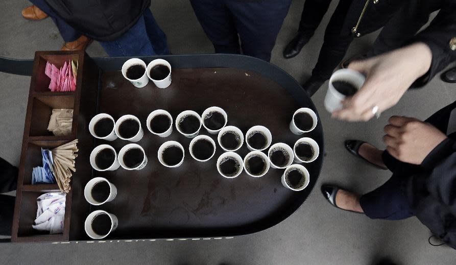 People standing in line reach for small cups of coffee before the Starbucks annual shareholder meeting, Wednesday, March 22, 2017, in Seattle. (AP Photo/Elaine Thompson)