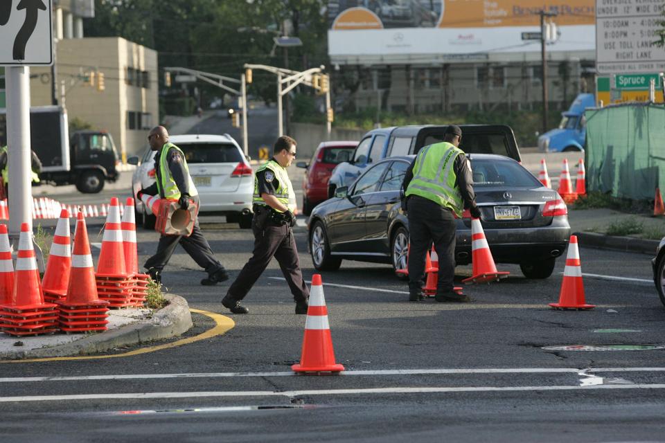 A Port Authority Police Officer and Maintenance Crews remove the traffic cones opening all lanes and toll booths to the George Washington Bridge at the intersection of Martha Washington Way and Bruce Reynolds Blvd Friday morning, September 13, 2013 at 8AM.