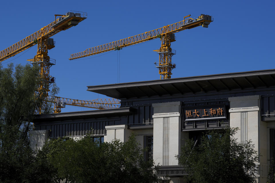 Construction cranes stand near an Evergrande new housing development showroom office building in Beijing on Sept. 22, 2021. China's central bank said Friday, Oct. 15, 2021 that financial risks from China Evergrande Group's debt problems are "controllable" and unlikely to spill over, amid growing investor concerns that the crisis could ripple through other developers. (AP Photo/Andy Wong)