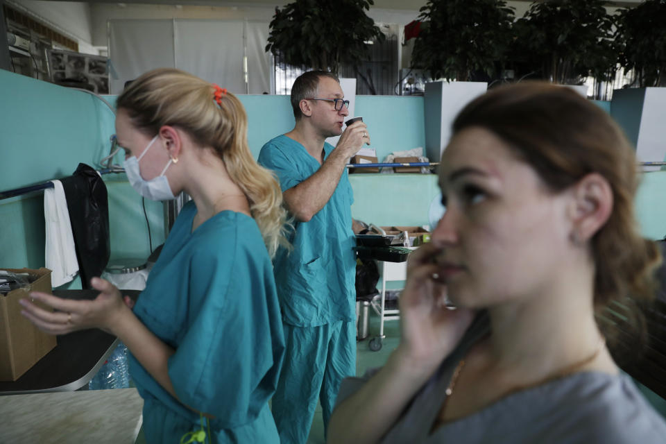 In this photo taken on Friday, May 15, 2020, Dr. Osman Osmanov, center, drinks a coffee as he has breakfast before his shift at an intensive care unit of the Filatov City Clinical Hospital in Moscow, Russia. Moscow accounts for about half of all of Russia's coronavirus cases, a deluge that strains the city's hospitals and has forced Osmanov to to work every day for the past two months, sometimes for 24 hours in a row. (AP Photo/Pavel Golovkin)