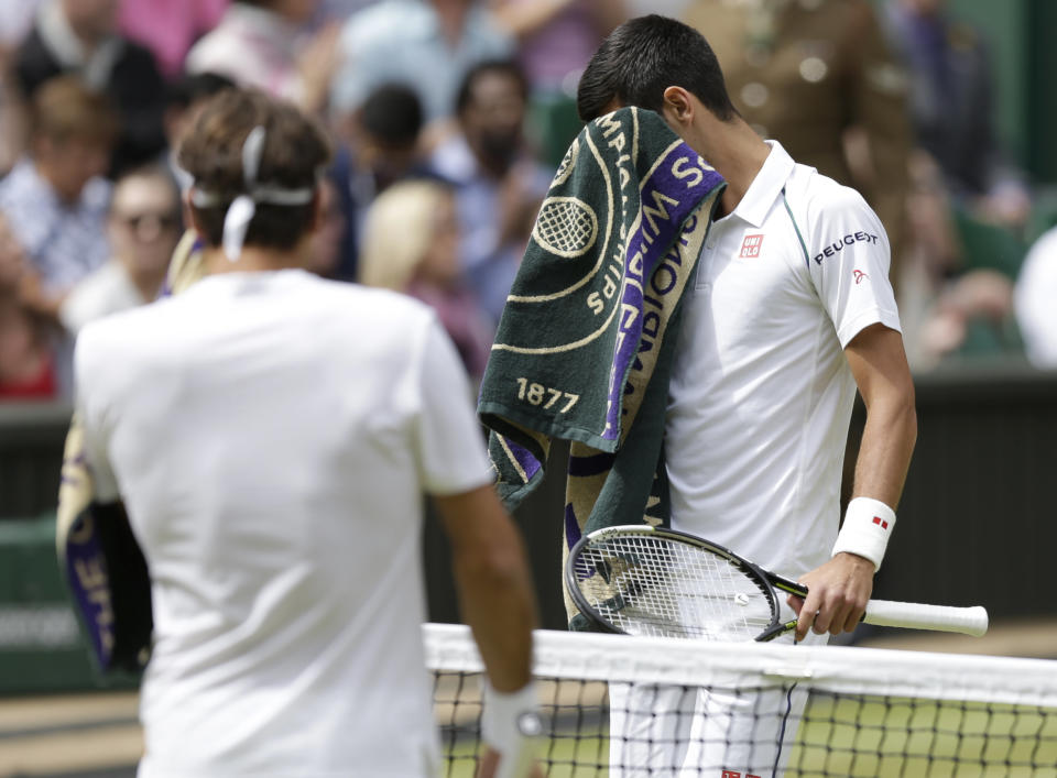 Novak Djokovic of Serbia, right, and Roger Federer of Switzerland wipe their faces during a change of end break during the men's singles final at the All England Lawn Tennis Championships in Wimbledon, London, Sunday July 12, 2015. (AP Photo/Pavel Golovkin)