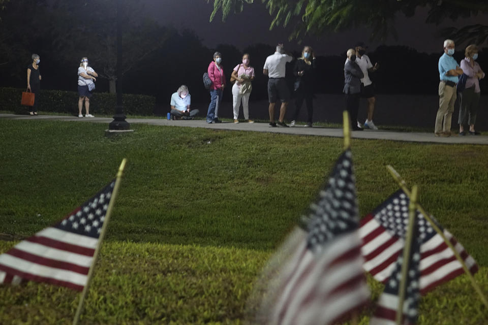 Voters wait in the dark before polls open on the first day of in-person early voting in Florida, at the Spanish River Library in Boca Raton, Monday, Oct. 19, 2020. (Joe Cavaretta/South Florida Sun-Sentinel via AP)