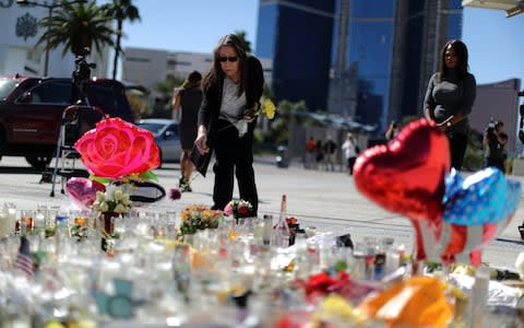 A woman leaves flowers at a makeshift memorial on the Las Vegas Strip - Credit: Reuters