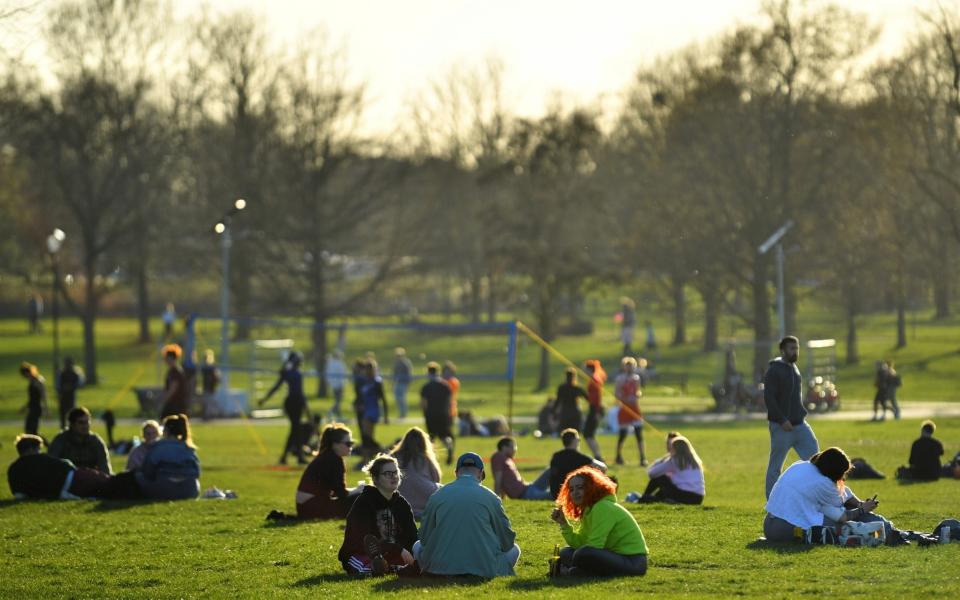 People sit on the grass as the sun sets on Clapham Common, following the easing of lockdown restrictions and the return of the 'rule of six' yesterday - REUTERS/Dylan Martinez