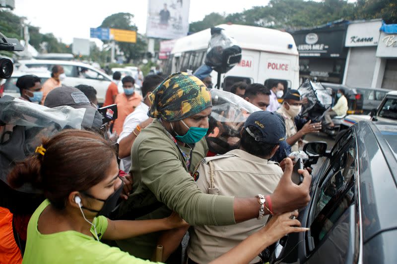 A policeman holds off media personnel as they surround a car carrying Bollywood actor Rhea Chakraborty as she heads to CBI office for questioning, in Mumbai