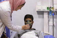 A medic helps a man suffering breathing difficulties after inhaling chlorine gas from Monday's toxic gas explosion at a private hospital in Jordan's Red Sea port of Aqaba, Tuesday, June 28, 2022. A crane loading chlorine tanks onto a ship on Monday dropped one of them, causing an explosion of toxic yellow smoke that killed over a dozen people and sickened some 250, authorities said. (AP Photo/Raad Adayleh)