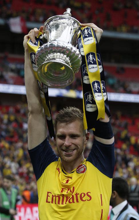 Arsenal's German defender Per Mertesacker celebrates with the trophy after winning the FA Cup final football match against Aston Villa at Wembley stadium in London on May 30, 2015