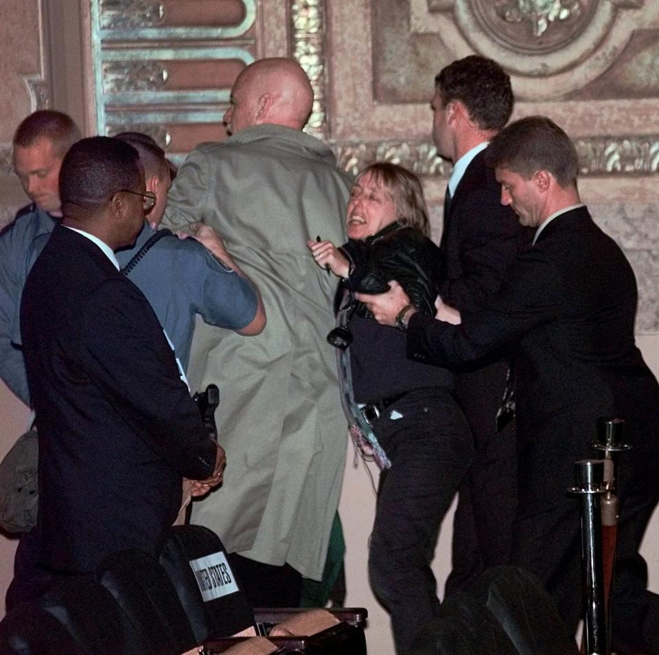 FILE - In this Nov. 30, 1999, file photo, two anti-World Trade Organization protesters, center, are escorted out of the Paramount Theatre in downtown Seattle by authorities after they stepped onstage and began speaking into the microphone. Saturday, Nov. 30, 2019 marks 20 years since tens of thousands of protesters converged on Seattle and disrupted a major meeting of the World Trade Organization. The protesters’ message was amplified not just by their vast numbers but by the response of overwhelmed police, who fired tear gas and plastic bullets and arrested nearly 600 people. Two decades later, many of their causes are still relevant. (AP Photo/Elaine Thompson, File)