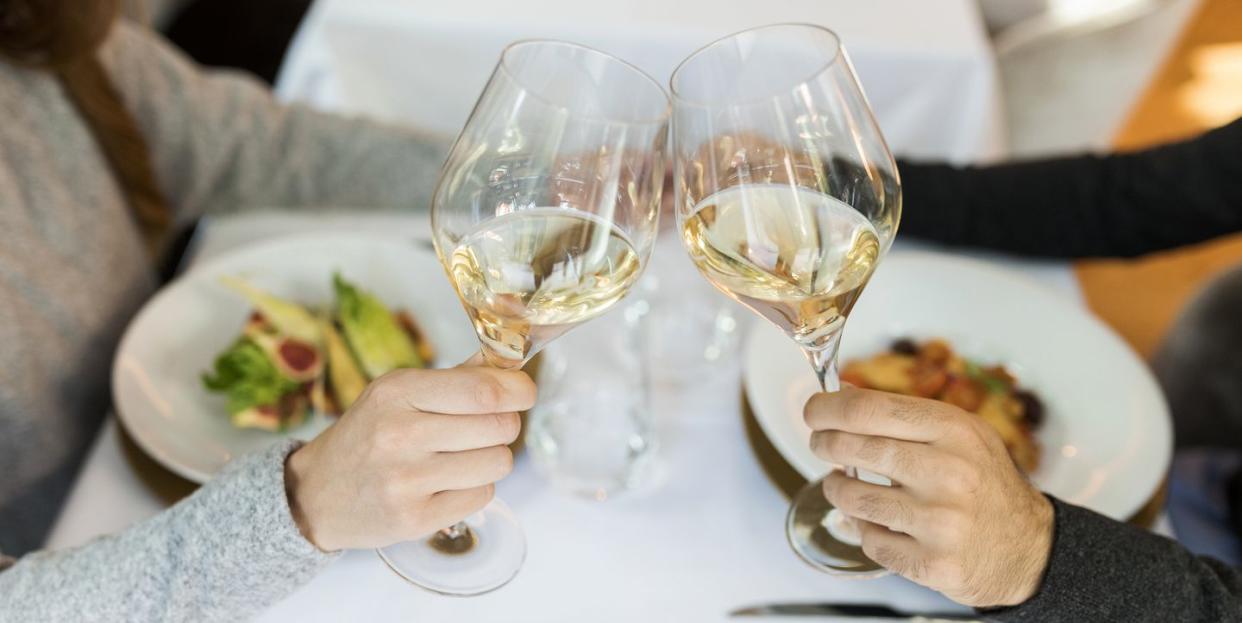 close up of couple clinking wine glasses in a restaurant