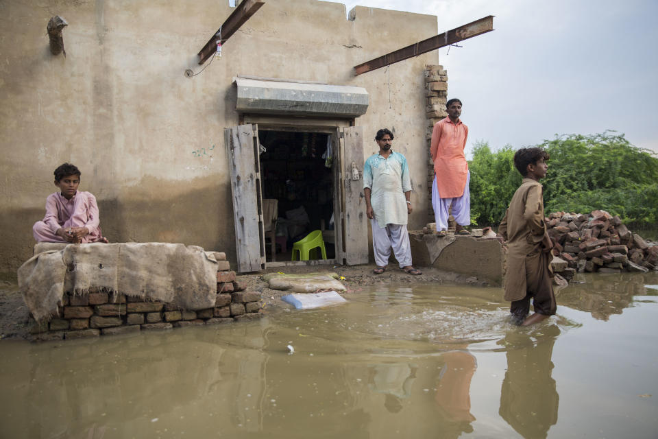 People stand outside a flooded property in one of the worst-hit areasSaiyna Bashir/Arete/WFP Asia