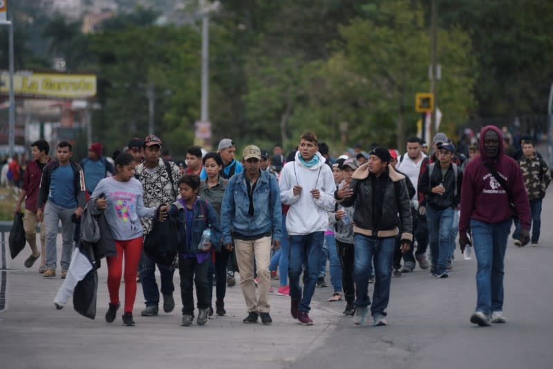 People, part of a caravan of migrants heading toward the United States, walk along a road in Agua Caliente